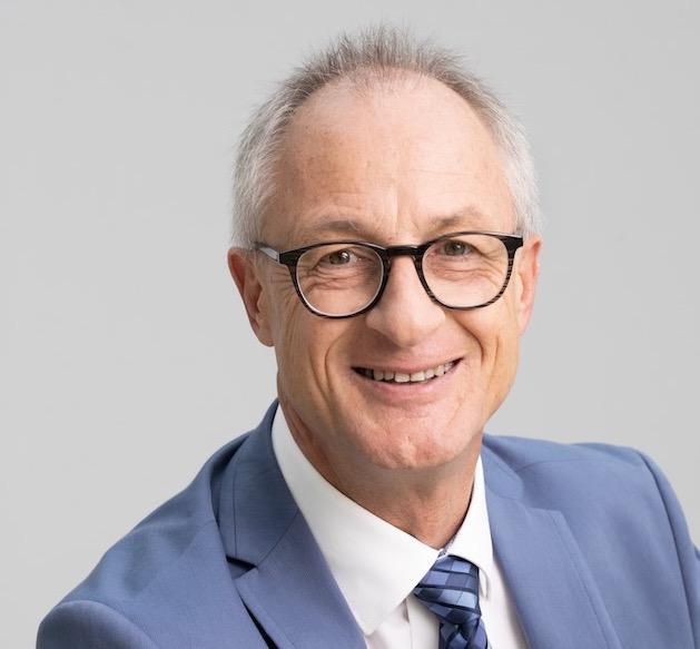 A friendly pastor in a formal suit speaking in a church or congregation in Basel, Switzerland, to promote the mission and faith of ICF Basel.
