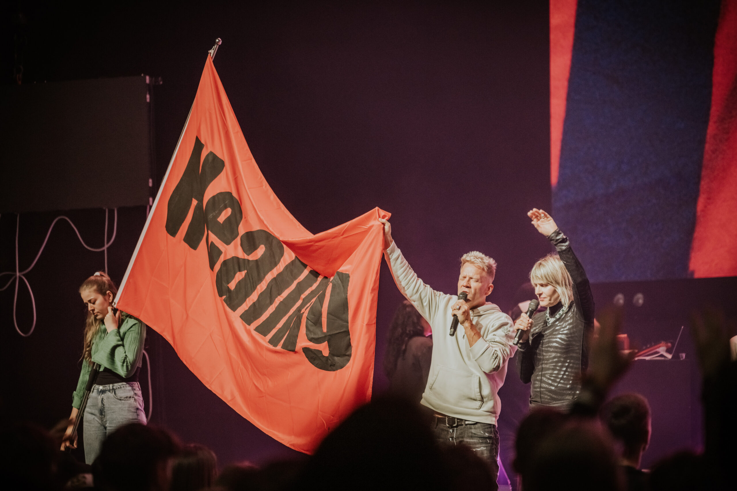 Menschen halten rote Flagge auf einer Bühne hoch