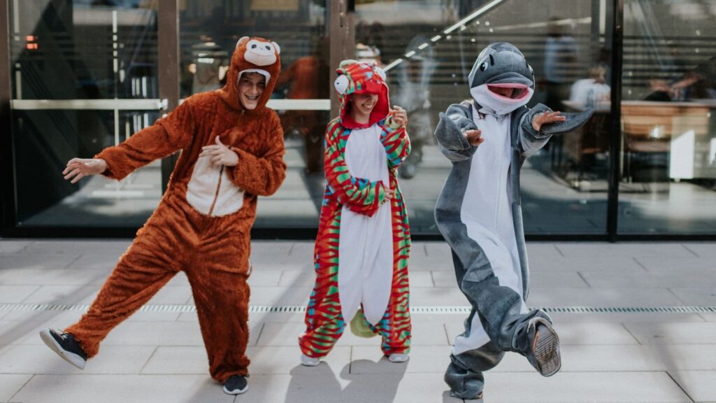 Kinder in Tierkostümen lachen und tanzen im Freien.