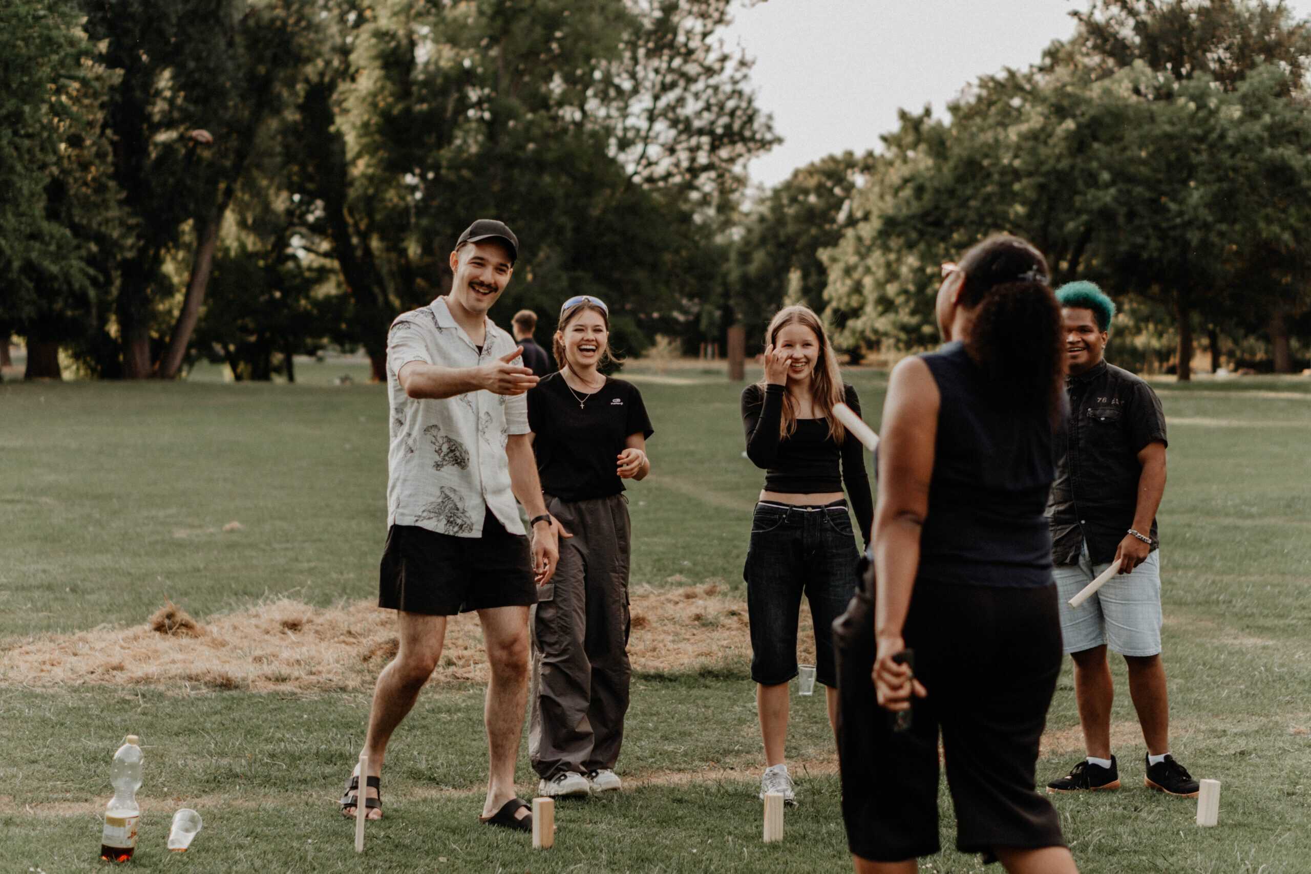 Fröhliche Gruppe junger Menschen beim Outdoorspiel im Park, lachend und spielend, ideal für Teambuilding, Gemeinschaft und Freizeitaktivitäten in Heilbronn, auf der Website der ICF Kirche Heilbronn.