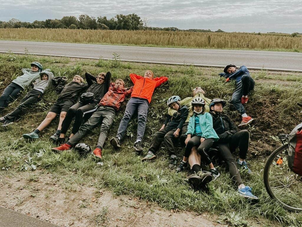 Gruppenbild von jungen Fahrradfahrern und Wanderern, die an einem Straßenrand im Grünen pausieren. Ideal für Aktivitäten im Freien, Familienausflüge oder Radreisen, passend für die Zielgruppe der Gemeinde ICF Mannheim.