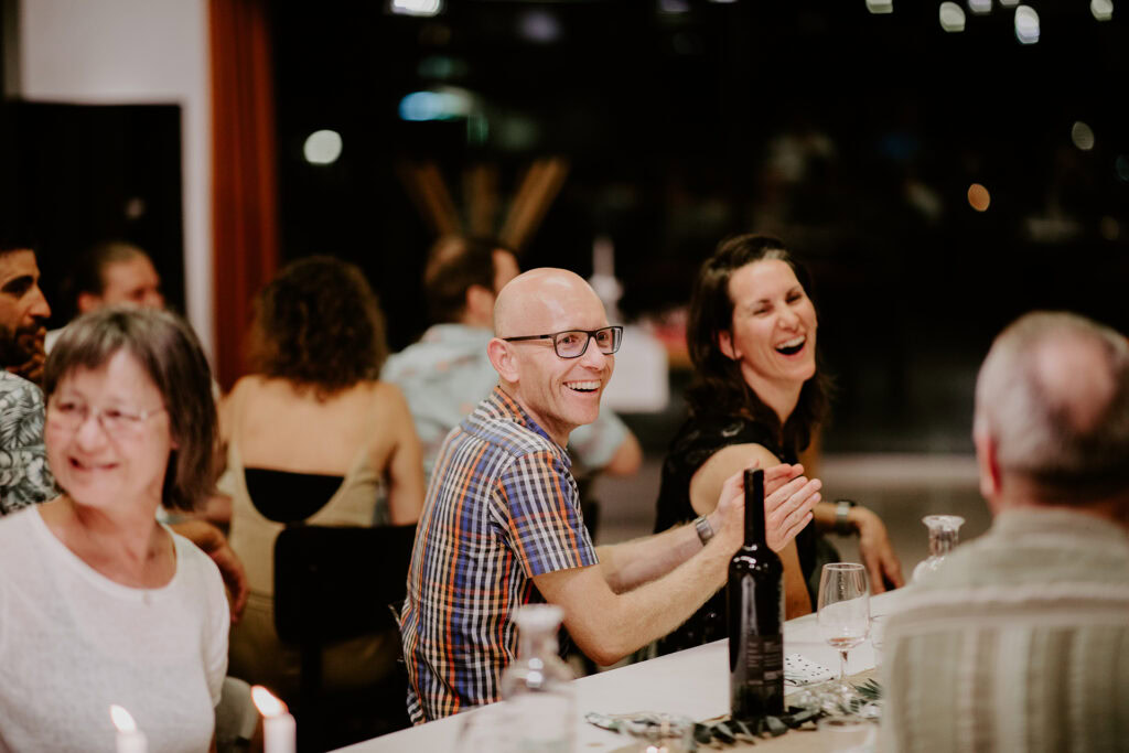 Menschen sitzen an einem Tisch, lachen und unterhalten sich.