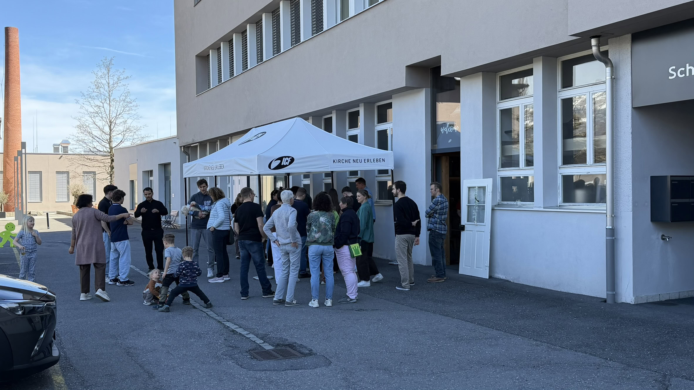 Menschen stehen in einer Warteschlange vor einem Gebäude mit Zelt.