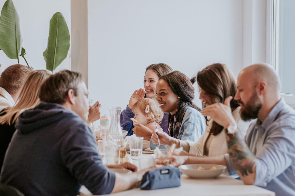 Menschen sitzen an einem Tisch beim gemeinsamen Essen.