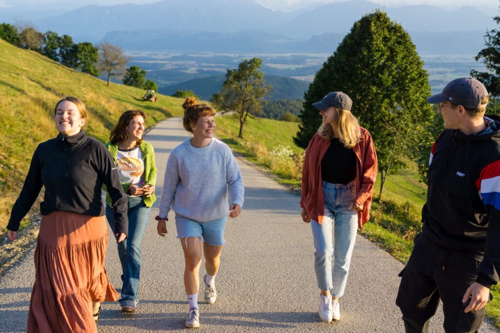 Sechs junge Menschen gehen auf einem Weg in einer ländlichen Umgebung.