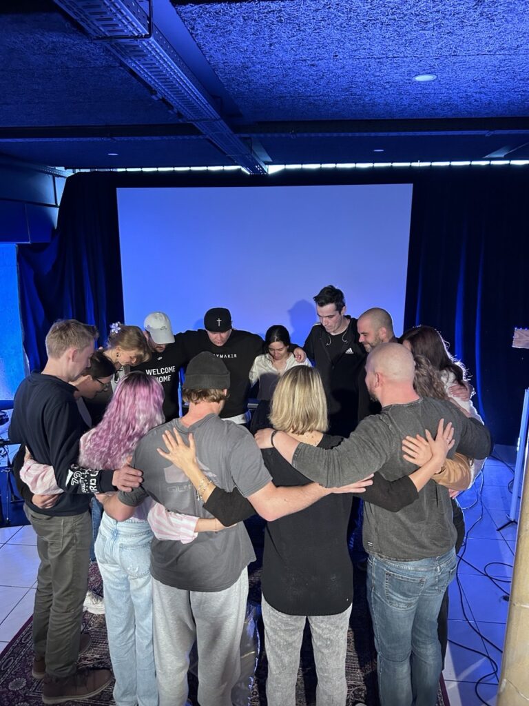 Gruppe von Menschen, die sich im Kreis mit den Händen auf den Schultern berühren.