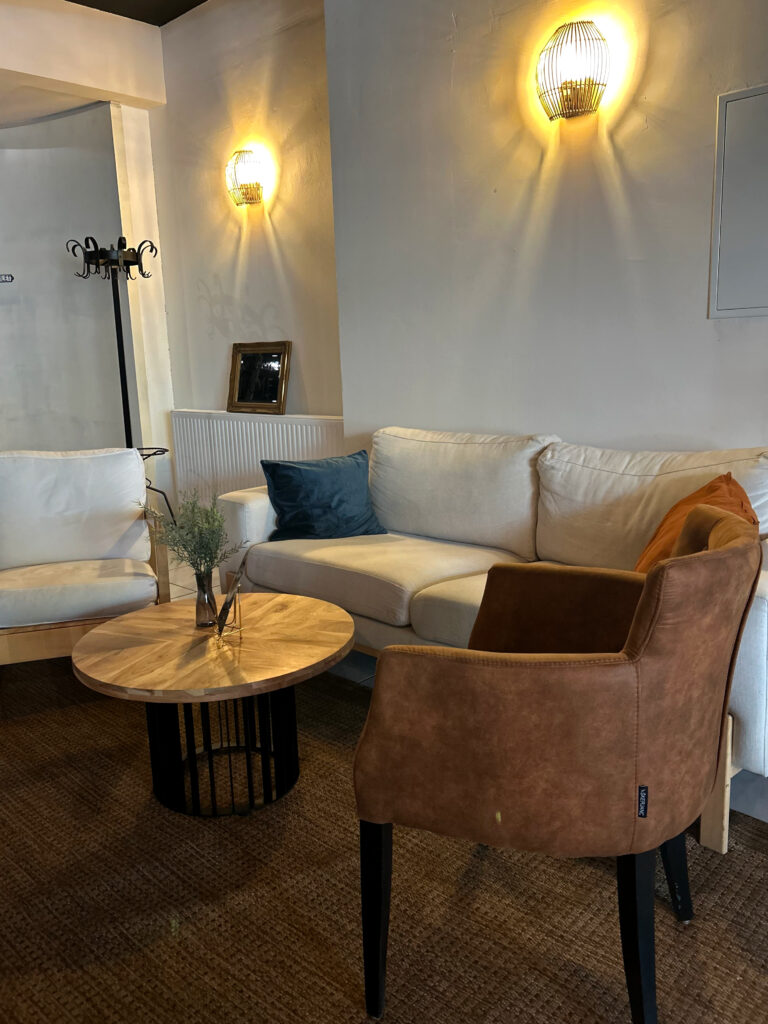 Wohnzimmer mit Sofa, Sessel, Tisch und Wandlampen.