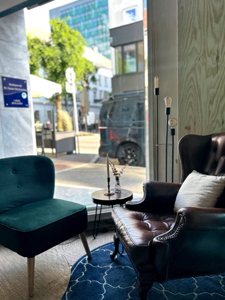 Zwei Sessel, ein kleiner Tisch und eine Stehlampe vor einem Fenster.
