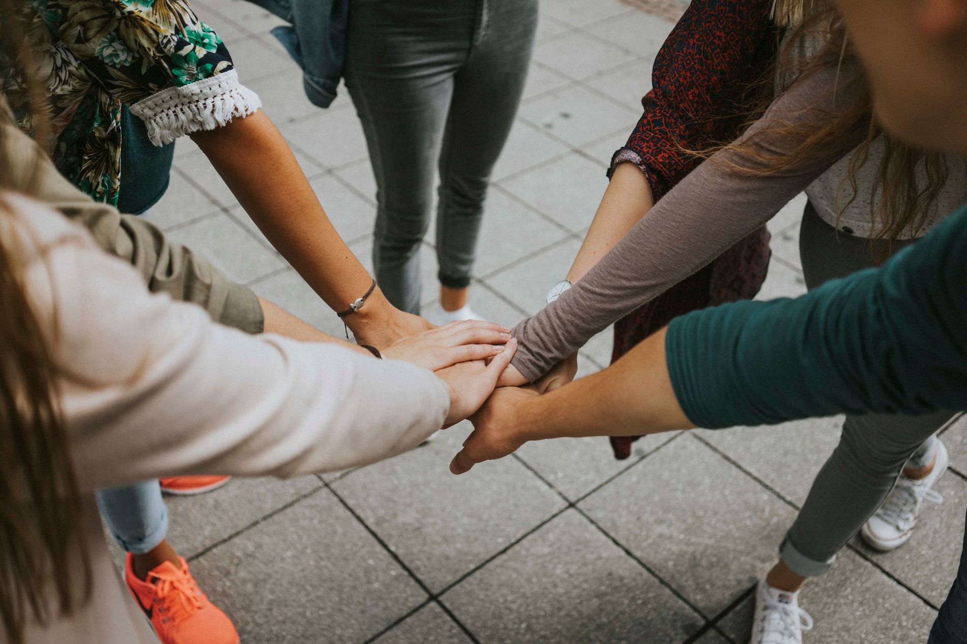 Six people placing their hands together in a circle.