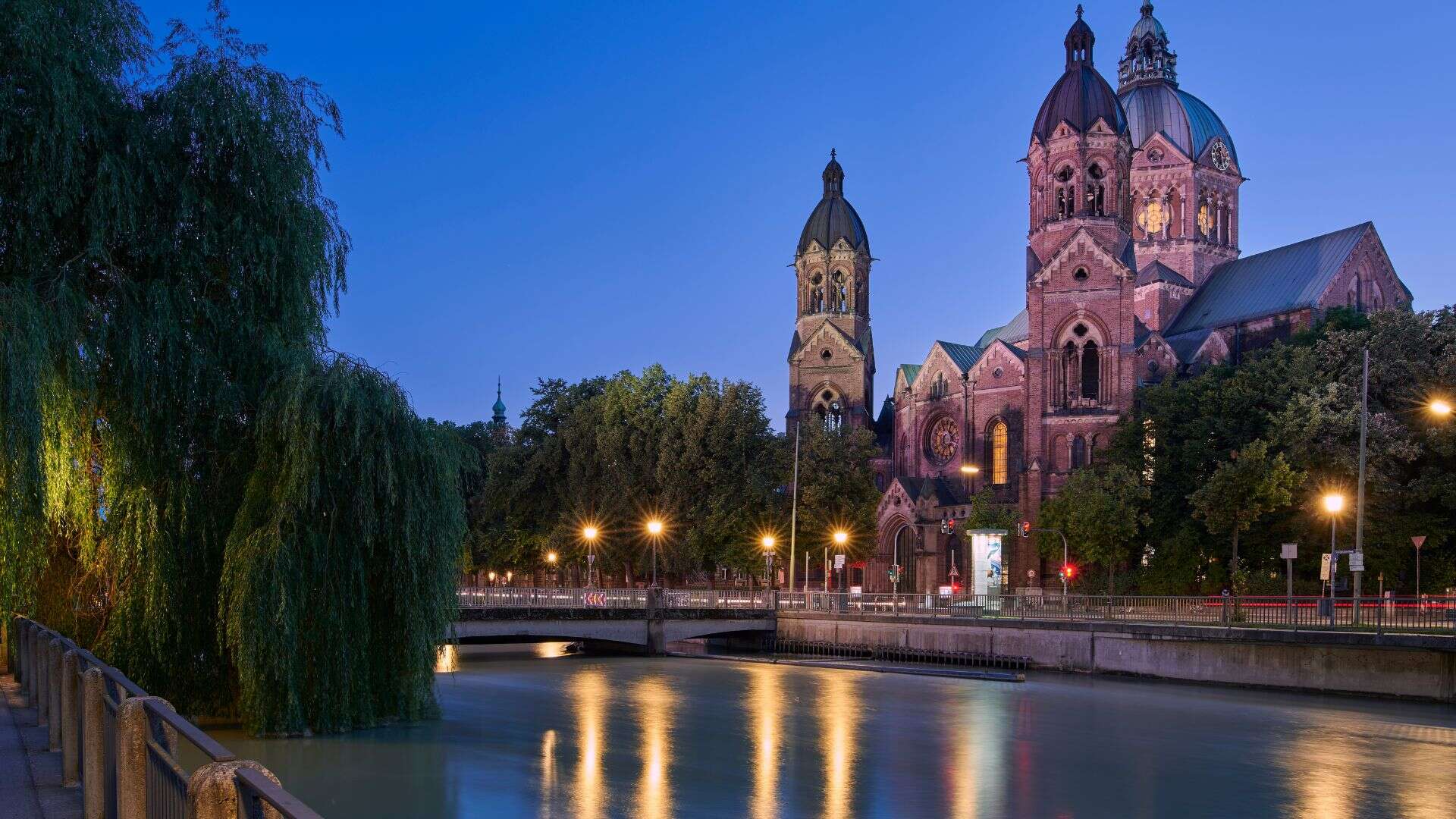Blick auf die beeindruckende Kirche in der Abenddämmerung entlang der Isar in München, symbolisiert Gemeinschaft und Glauben im Herzen der Stadt.