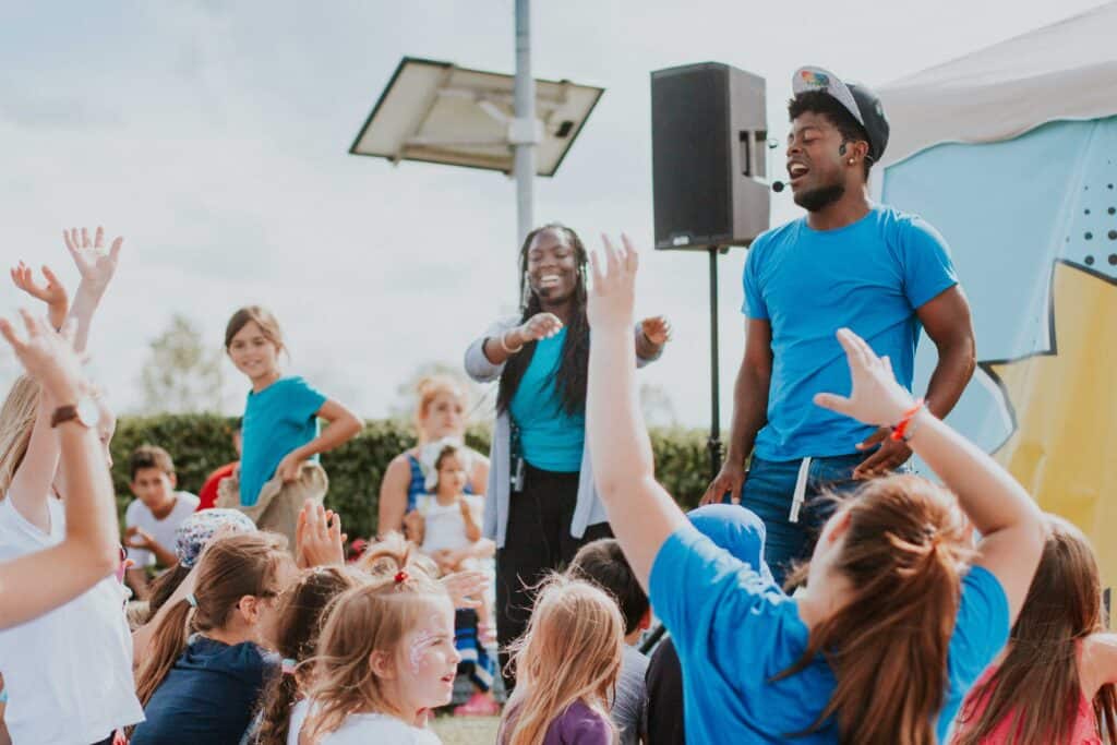 Happy children and supervisors celebrate together at an outdoor youth event in Munich - fun, music and community.