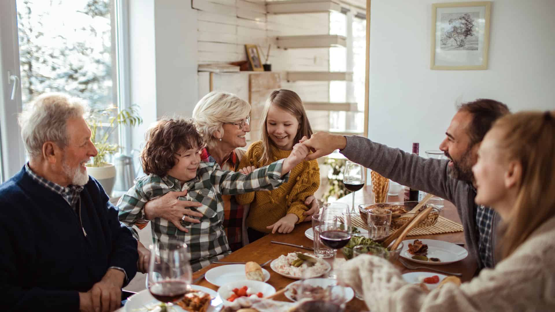 Alt Text: Families eating together in the living room, laughing and sharing meals, conveying a warm, friendly atmosphere in a Christian community.