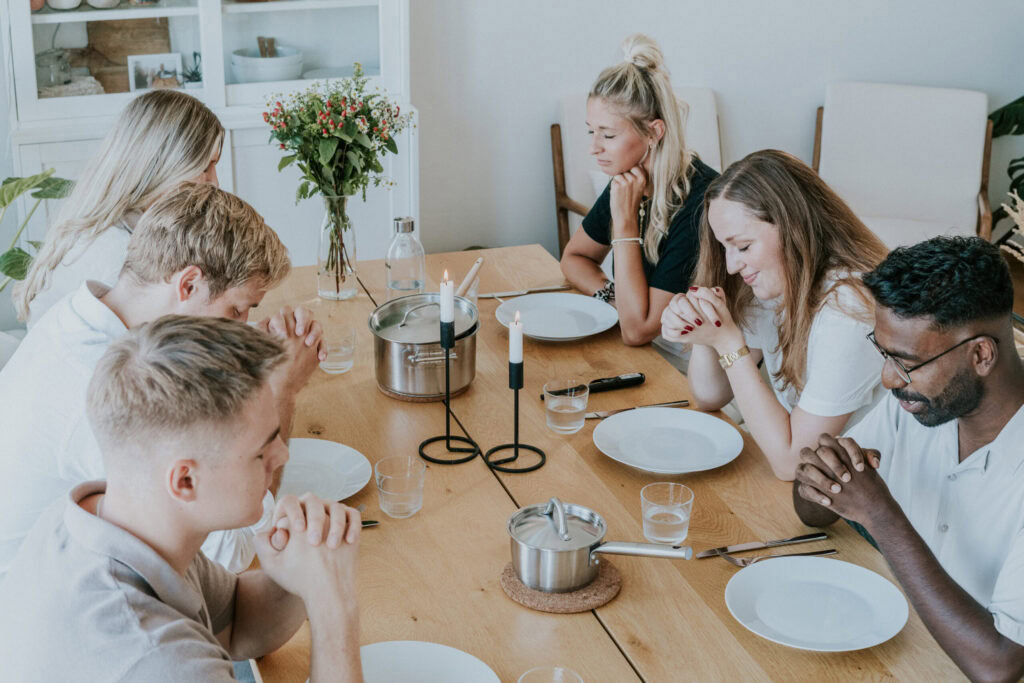 Family of six sitting at a wooden table for dinner.