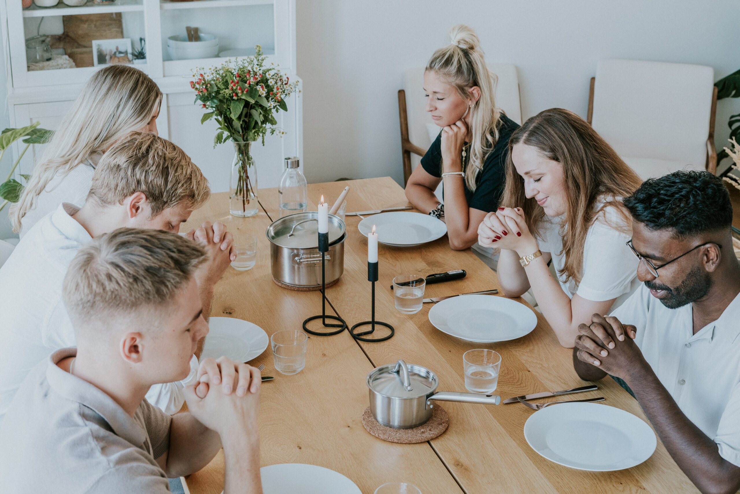 Family of six sitting at a wooden table for dinner.