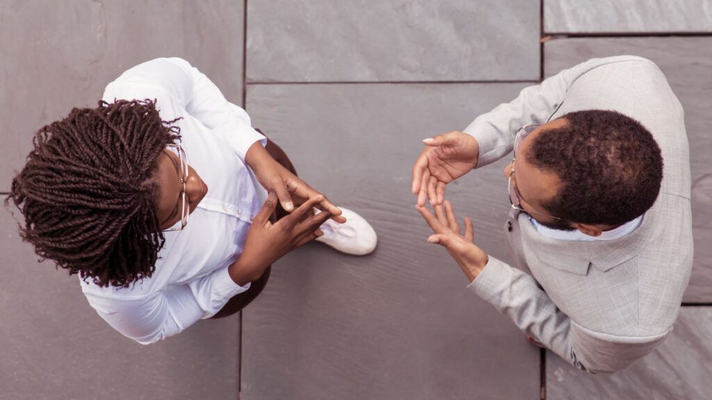 Two people stand opposite each other, one person shakes the hand of the other.