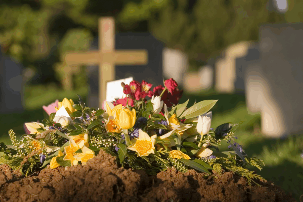 Flowers lie on the ground in front of a gravestone in the cemetery.