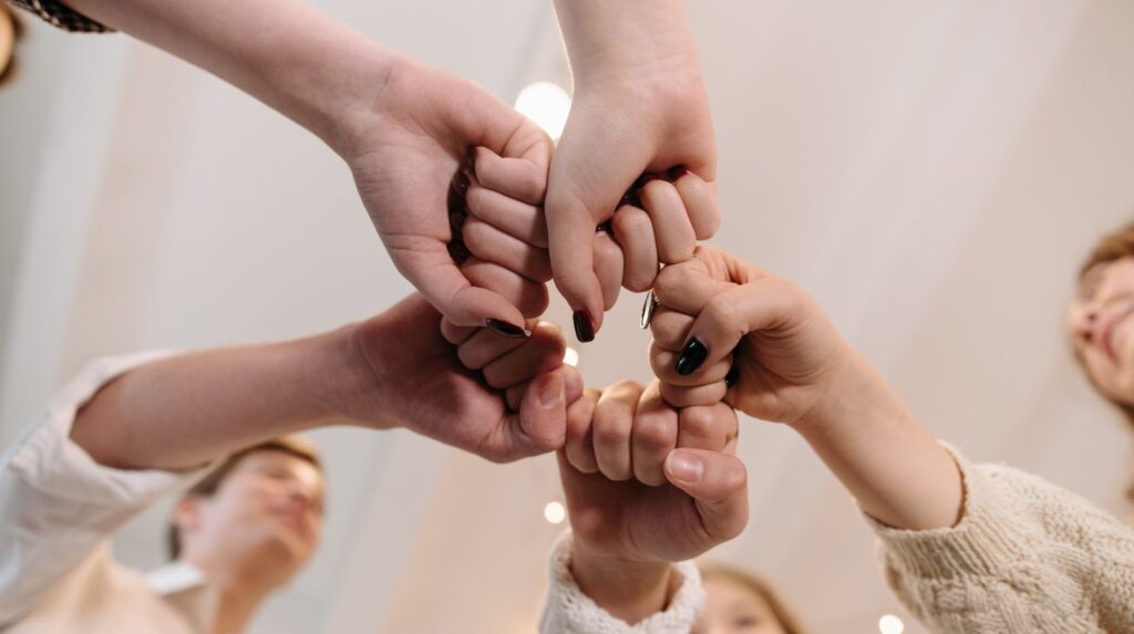 Four hands that touch in the middle and form a circle.