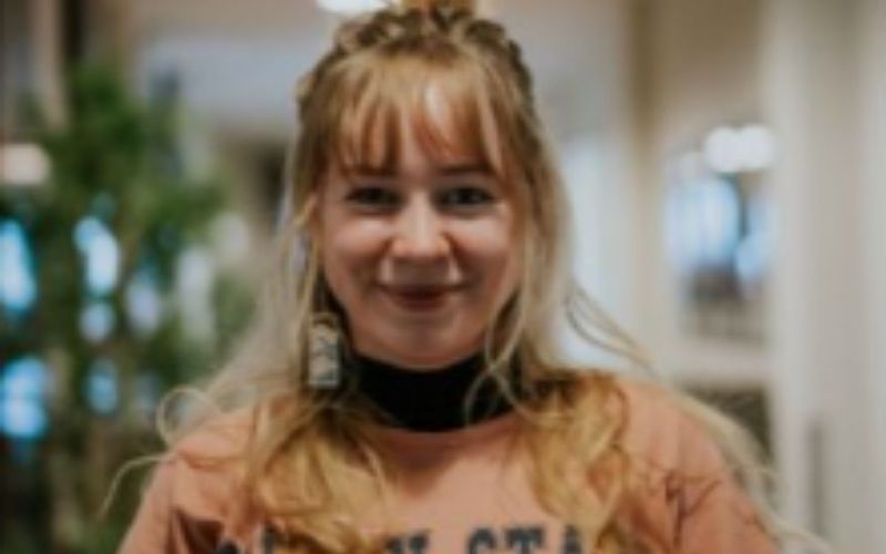 A young girl with blonde hair smiling in an interior.