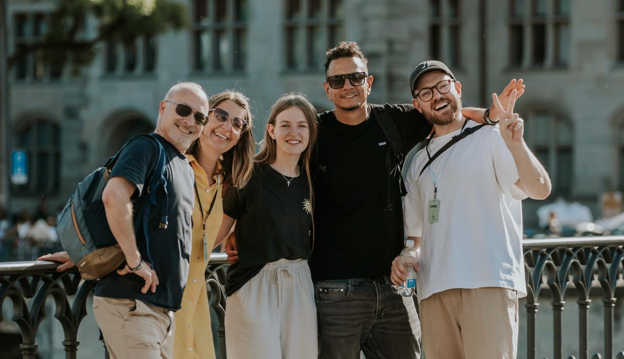 Group photo of five friends standing on a bridge and smiling.