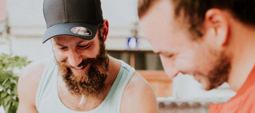 Two men are laughing while cooking in a kitchen.