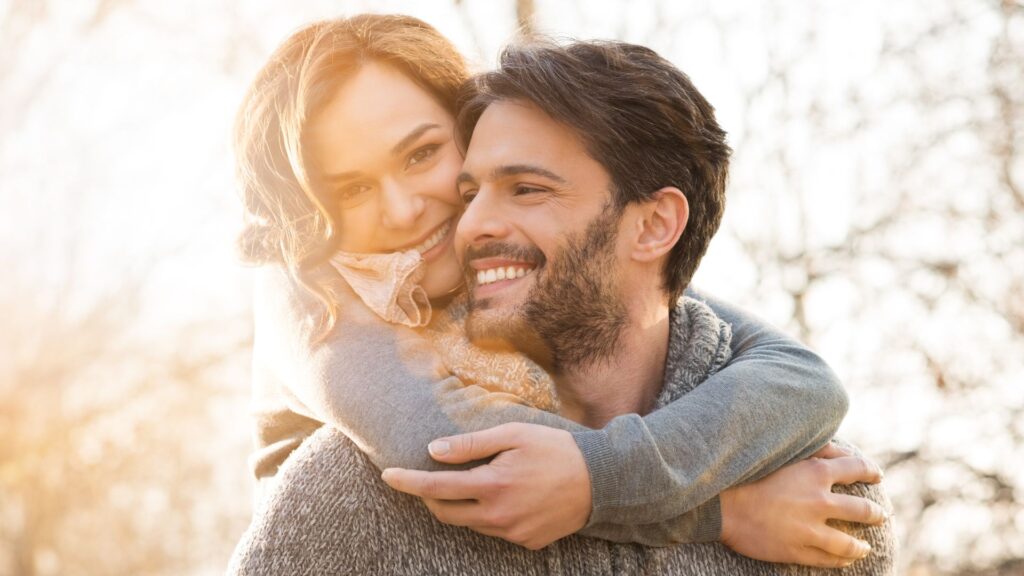 A man and a woman embrace outside at sunset.