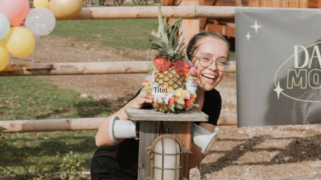 Frau hält einen Obstkorb mit Ananas und Früchten, lächelt.