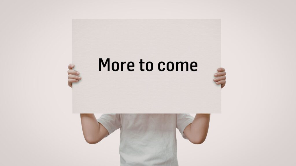 Person hält ein weißes Schild mit der Aufschrift "More to come".