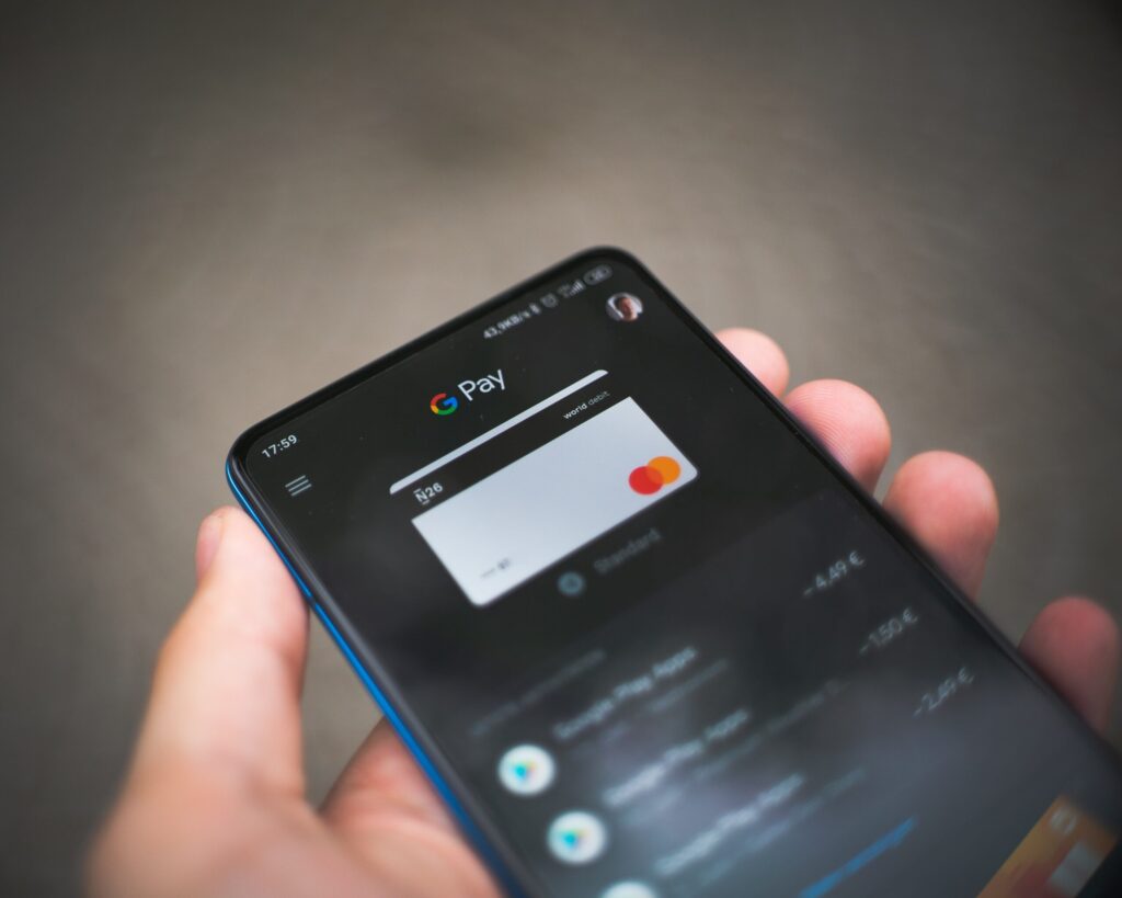 Smartphone zeigt Google Pay App mit Mastercard-Logo, in der Hand gehalten.