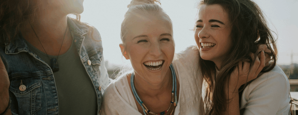 Alt Tag: Fröhliche Frauen lachen zusammen, Gefühl von Gemeinschaft und Freude, in einem lichtdurchfluteten Raum, Symbol für positive Verbindung und Zusammenhalt.