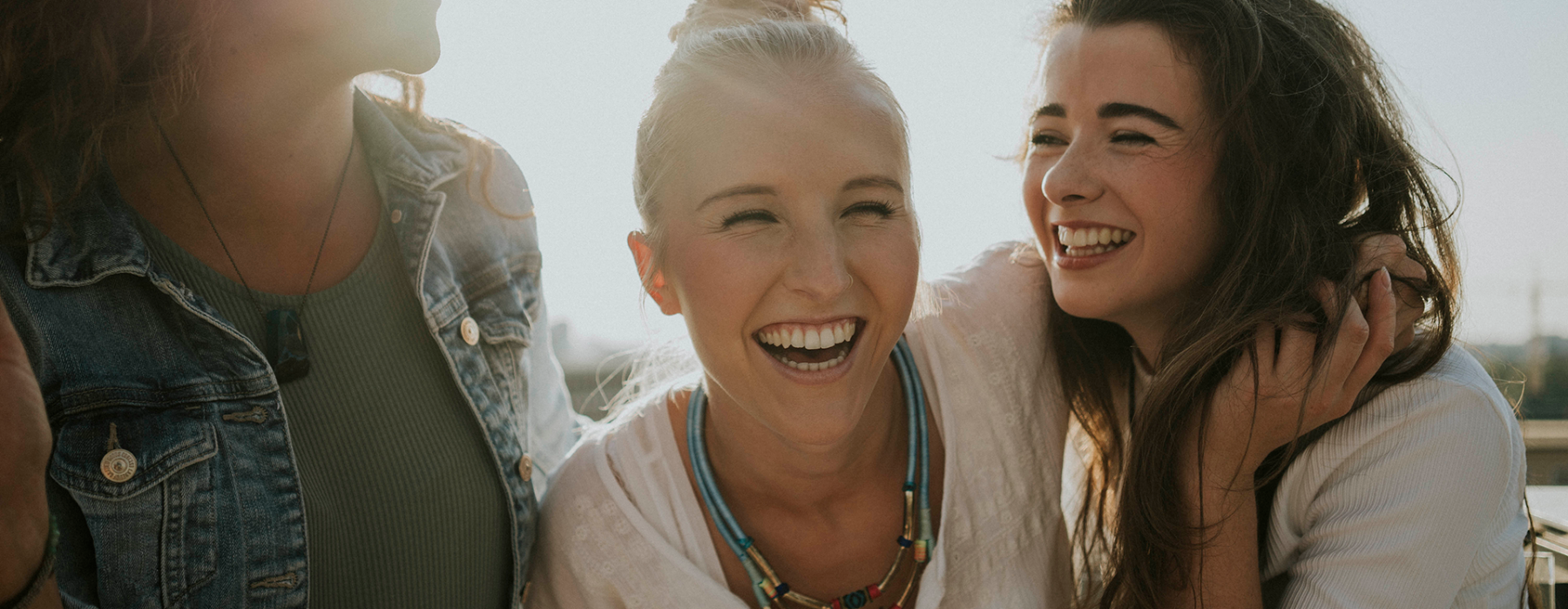 Alt Tag: Fröhliche Frauen lachen zusammen, Gefühl von Gemeinschaft und Freude, in einem lichtdurchfluteten Raum, Symbol für positive Verbindung und Zusammenhalt.