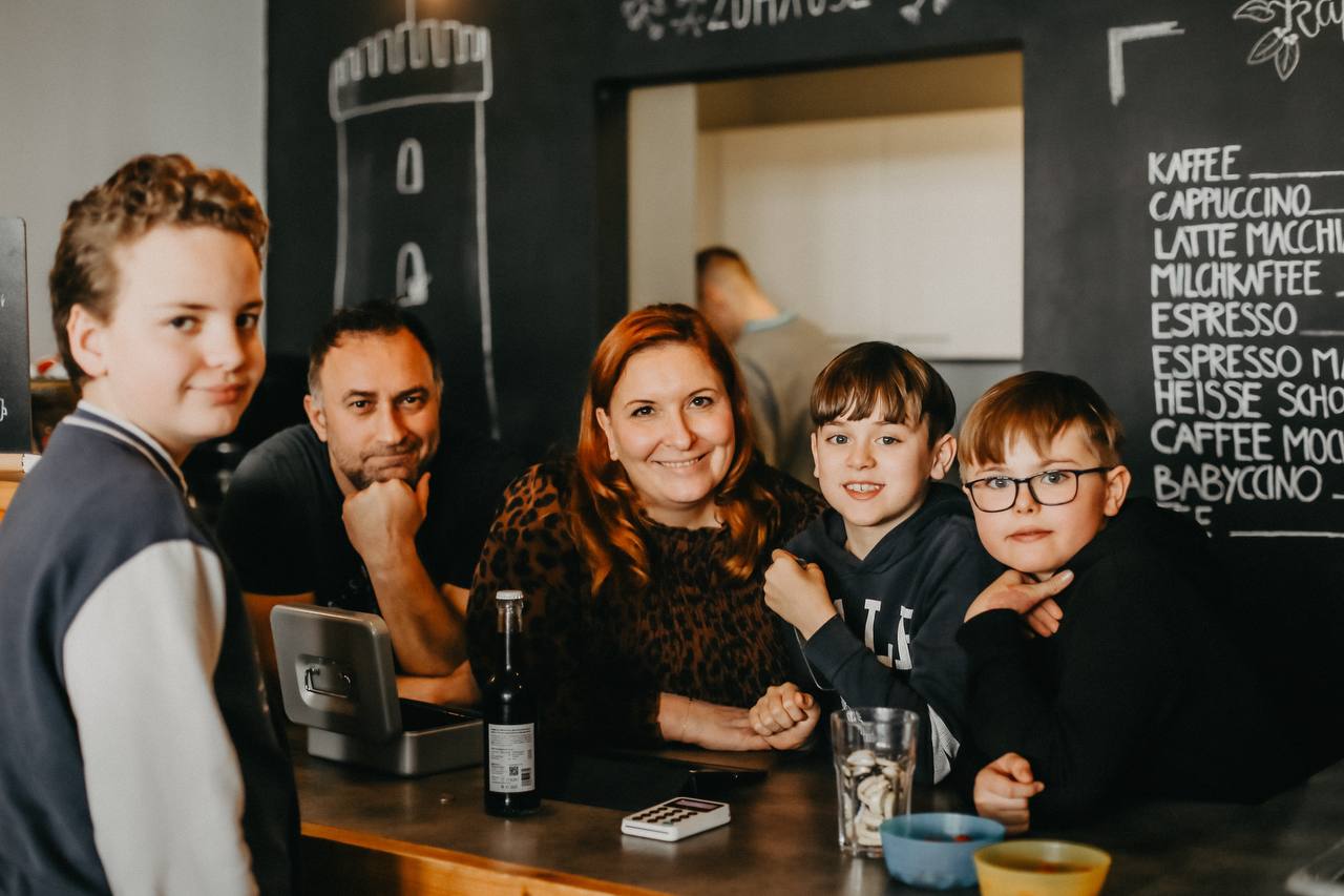 2 Erwachsene Personen und 3 Kinder lehnen auf einem Tresen und gucken glücklich in die Kamera