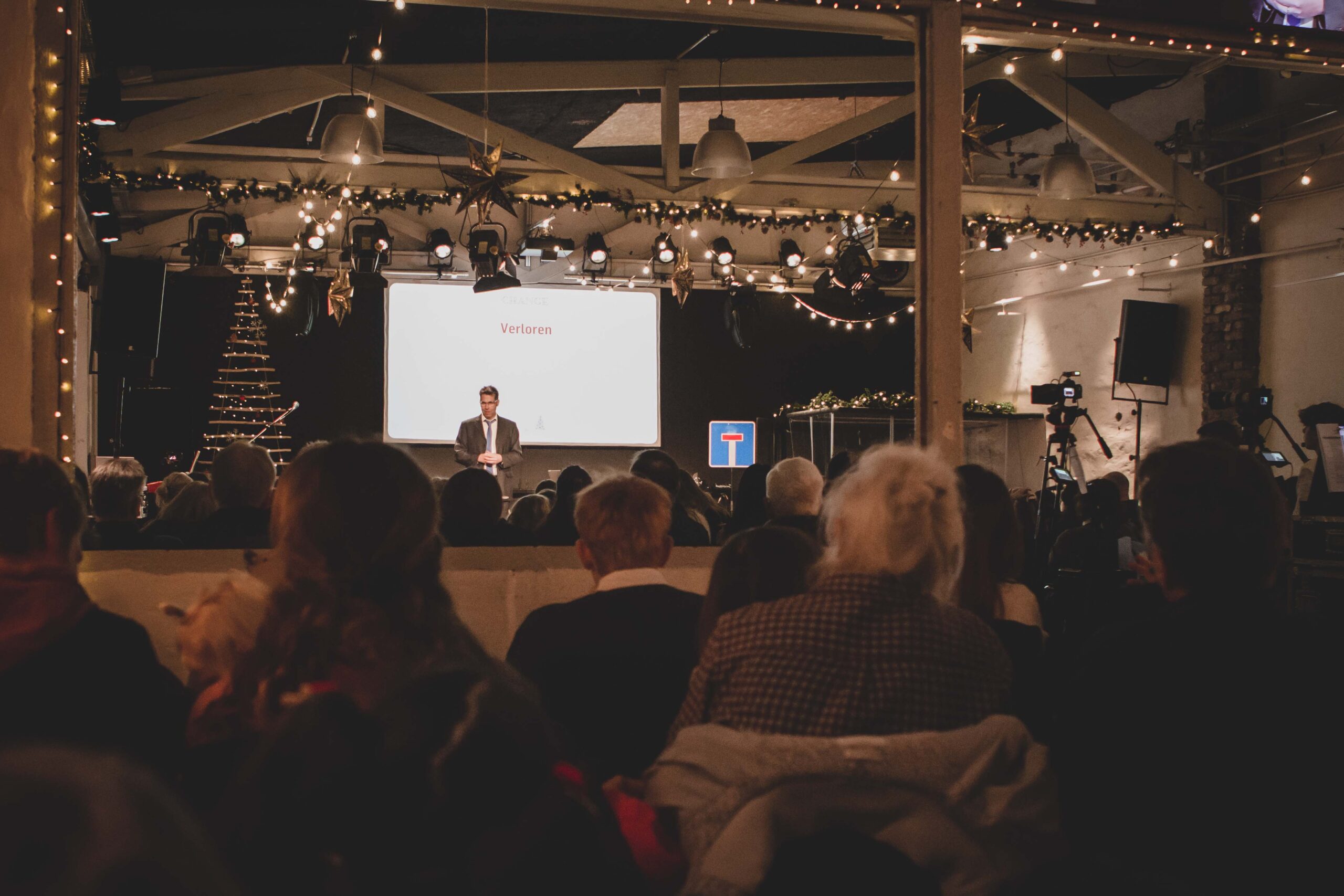 Moderne Kirchenveranstaltung in festlichem Ambiente, mit Gemeinde im Vordergrund, Bühnen- und Medientechnik, festlicher Dekoration und weihnachtlicher Stimmung, bei der Gemeinschaft und Glauben im Mittelpunkt stehen.
