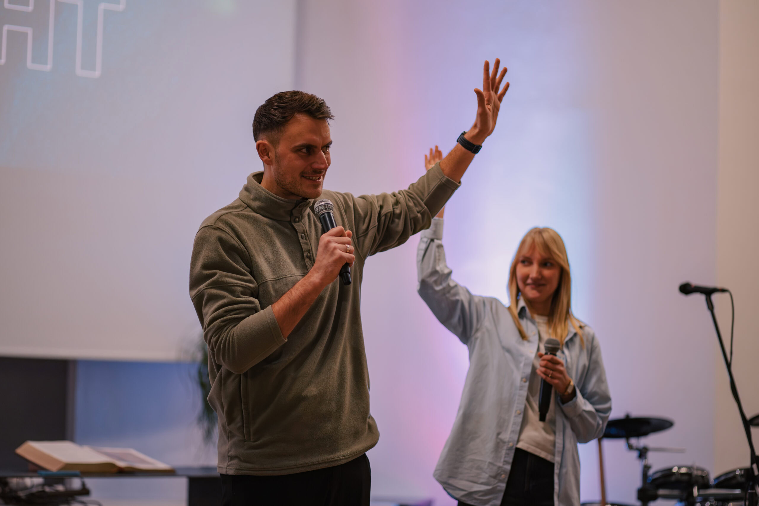 Zwei Personen sprechen auf einer Bühne bei einer ICF Hamburg Veranstaltung, einer hält ein Mikrofon, die andere winkt.