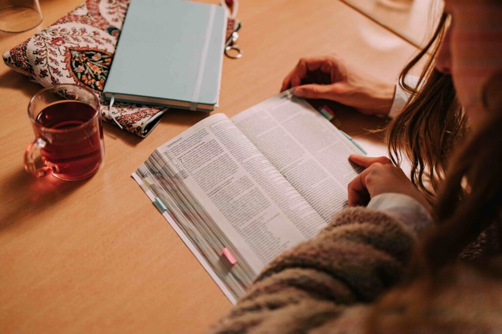 Person liest in der Bibel während der Vorbereitung eines Gottesdienstes bei ICF Hamburg, umgeben von Notizbüchern und einer Tasse Tee.