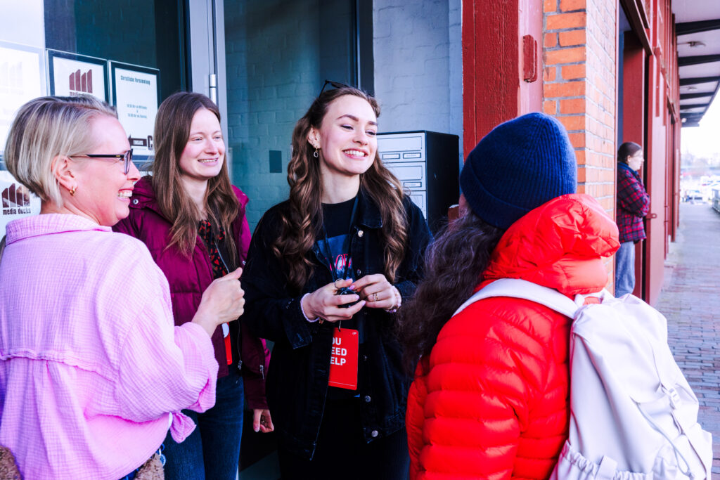 Drei Frauen und ein Mädchen stehen im Gespräch vor einem Gebäude.