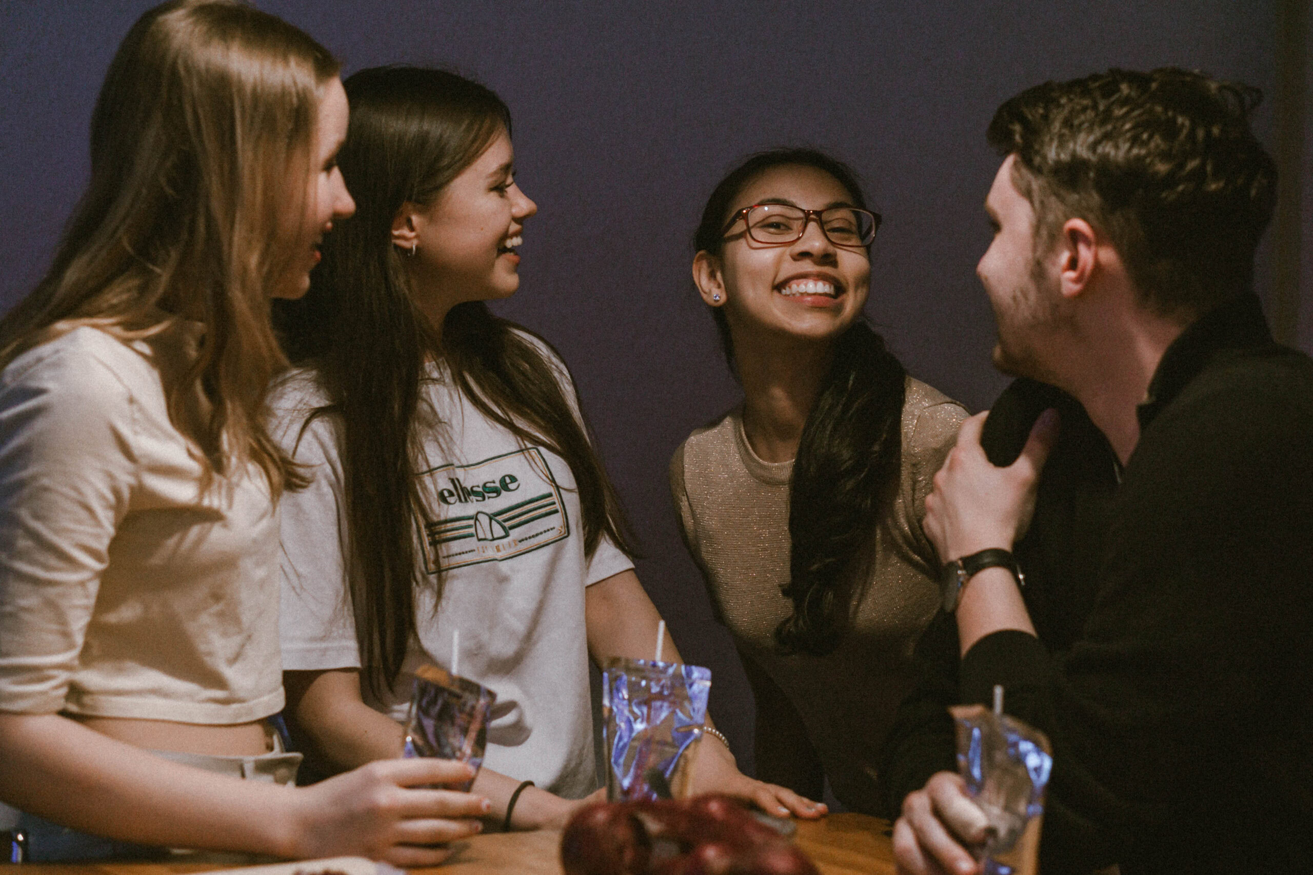 Vier Jugendliche, drei Frauen und ein Mann, sprechen und lachen miteinander.