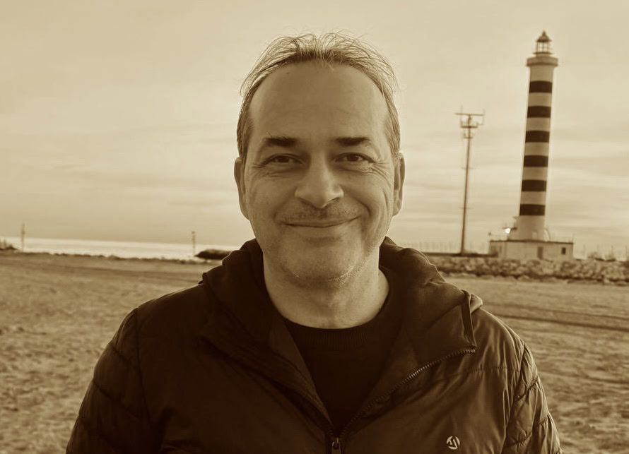 Ein Mann genießt den Blick auf den Leuchtturm am Strand an der Ostsee bei Sonnenuntergang in Mannheim. Perfektes Bild für Entspannung und Erholung am Meer.