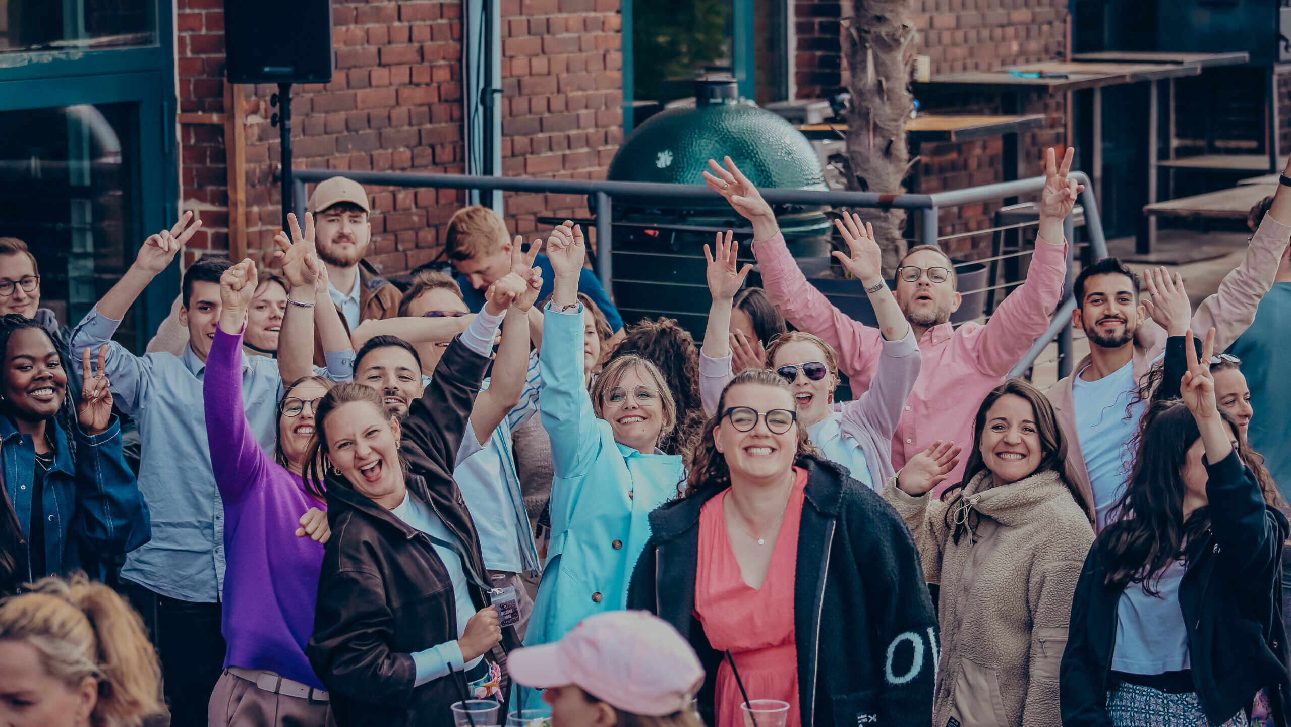 Mehrere Menschen stehen zusammen, einige heben die Arme und lachen.