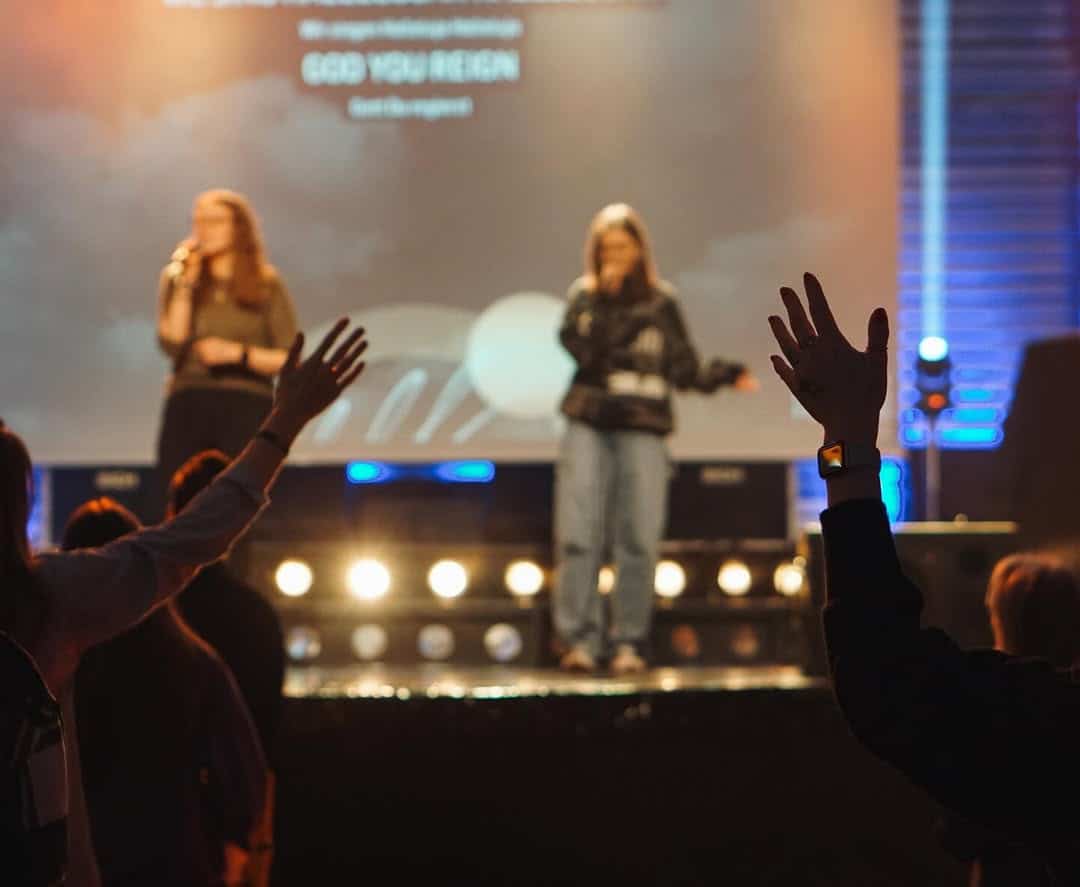 Menschen beim Gottesdienst in Wetzlar bei ICF XY, mit Gebetshandbewegungen, moderner Kirche, Gemeinschaft und spirituellem Erlebnis.