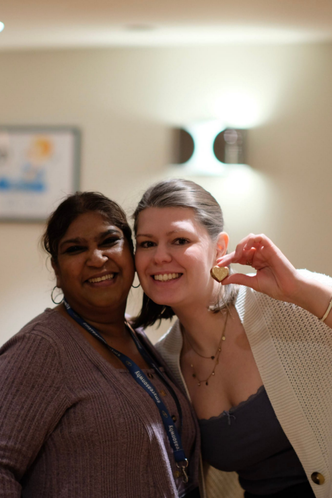 Zwei Frauen stehen nebeneinander, eine hält eine Medaille hoch.