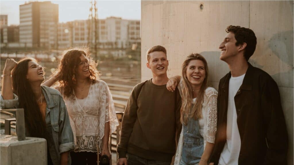 Cheerful young people laugh and chat in a relaxed atmosphere in front of the church in Munich.