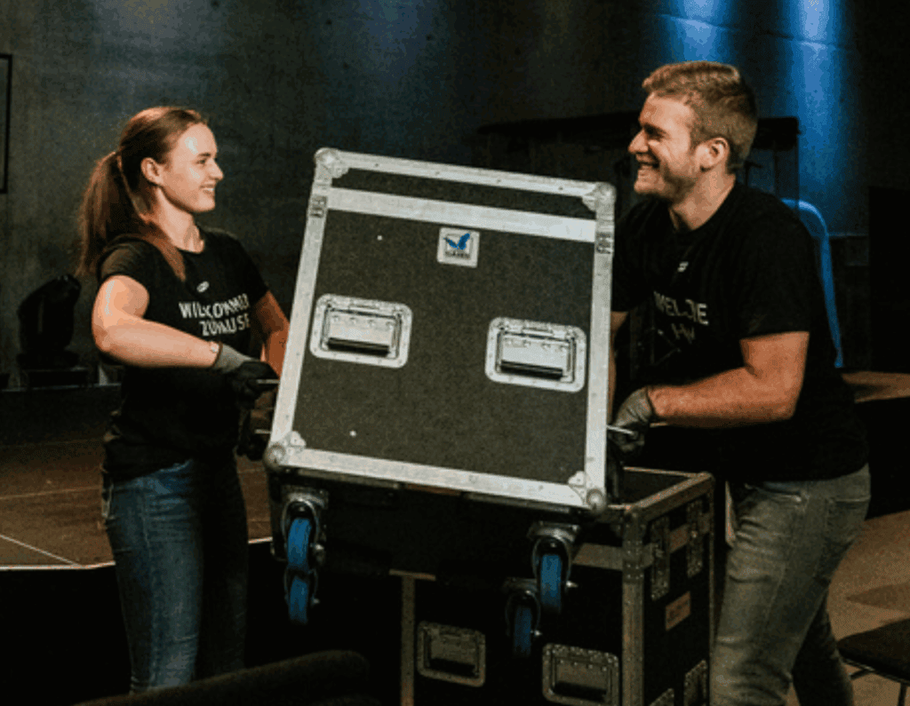 Two young people setting up professional event equipment at ICF Munich, which stands for modern Christian communities and events.