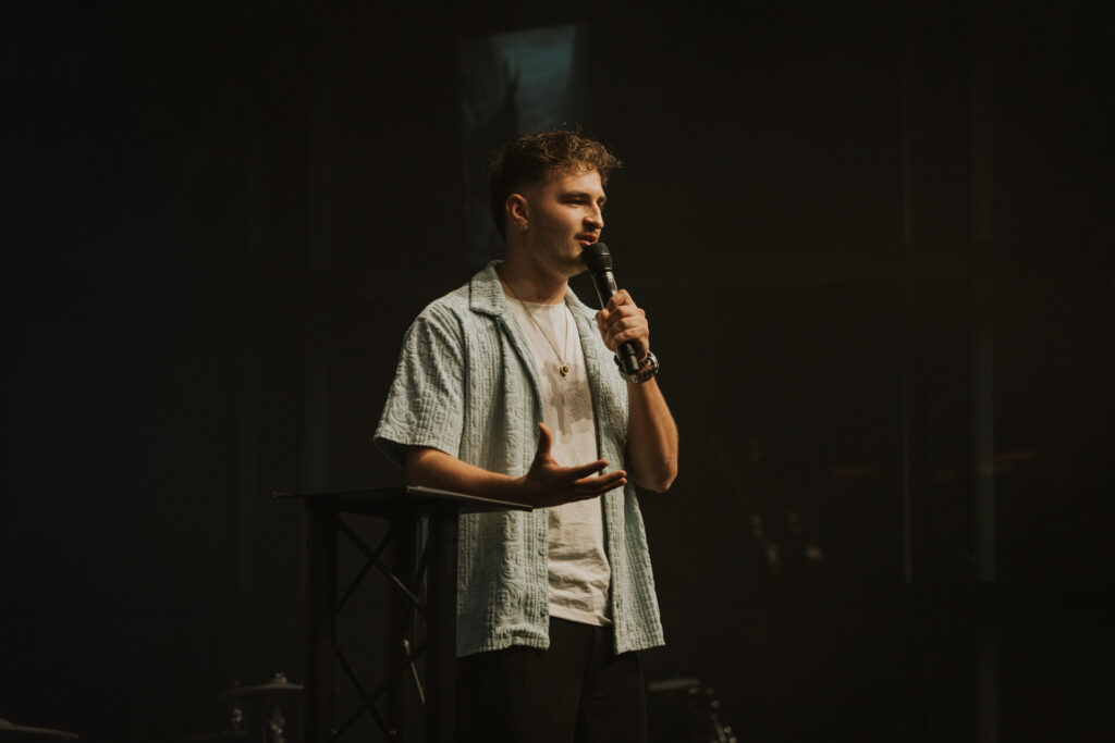 Junger Mann spricht bei Jugendgottesdienst, kreative christliche Veranstaltung, Community, Glaube, Inspiration, modern, Kirche Bern, Jugendinitiative, religiöse Zusammenkunft.