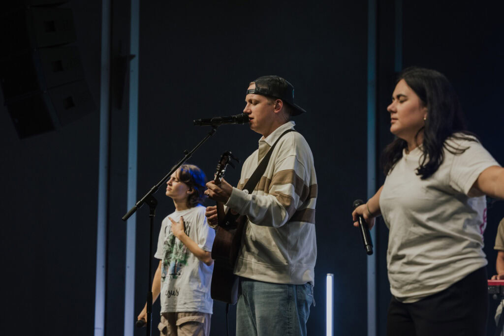 ALT-Text: Jugendliche beim Worship in der ICF Bern Gemeinde, singen und spielen Instrumente während eines Gottesdienstes in der modernen Kirche.