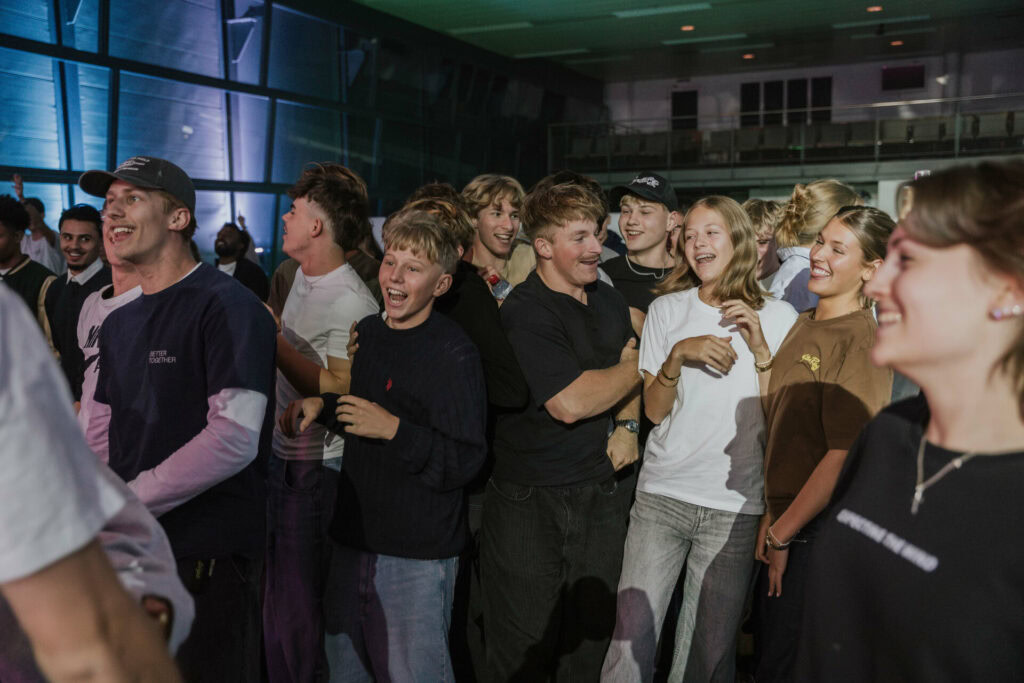 Junge Leute lachen und haben Spaß bei einer religiösen Veranstaltung im großen Saal, in einer modernen Kirche in Bern.