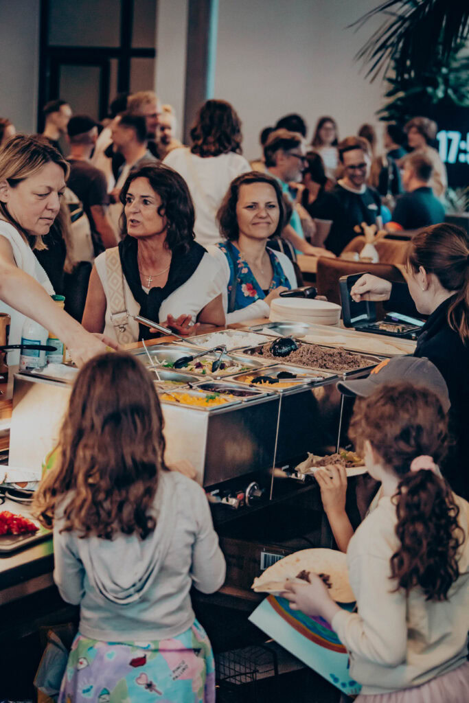 Alt: Menschen beim Essen und Austausch bei einer Veranstaltung der ICF Gemeinde in Mannheim, vielfältige Atmosphäre, Gemeinschaft, positive Stimmung, modernere Location.